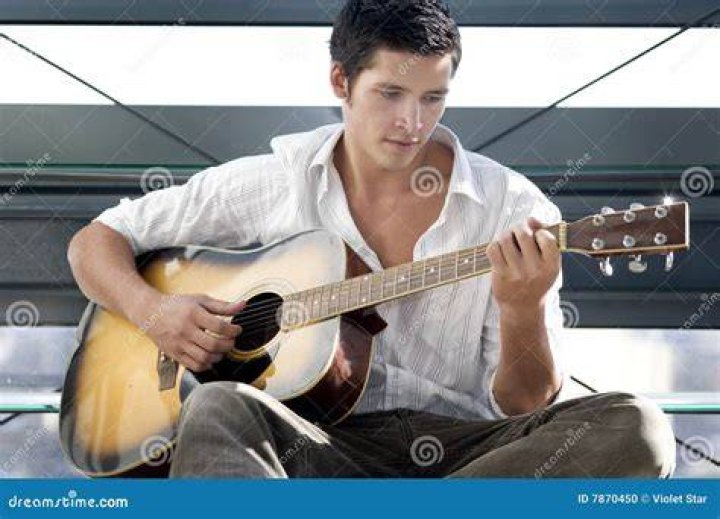A man plays a guitar and sings on a porch from Songcatcher