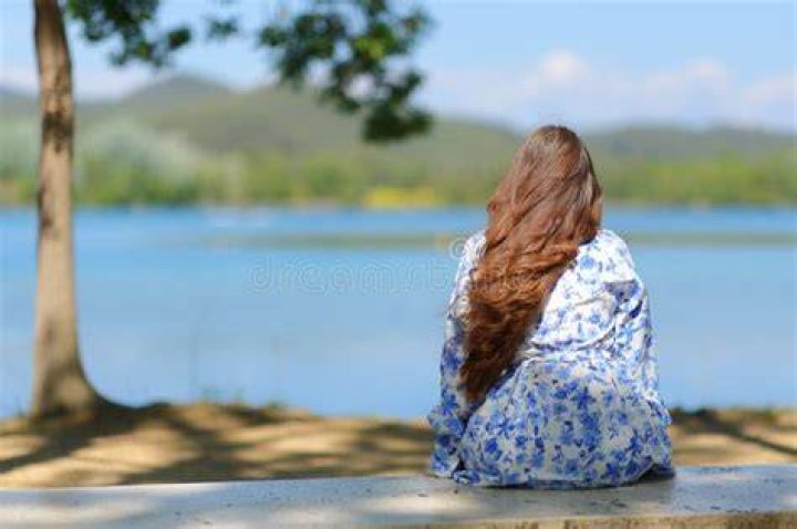 A woman contemplating in a meadow with a suitcase