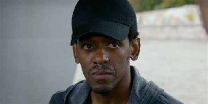 Adrian from Manifest wearing a baseball cap and looking off to the side.