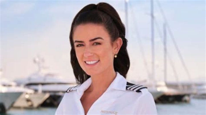 Aesha Scott from Below Deck Down Under's promo photo wearing blue shirt in front of yacht