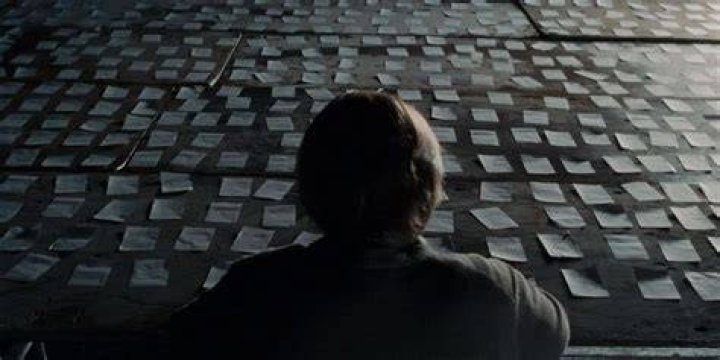 Caden staring at sheets of paper in Synecdoche New York