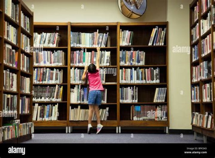 Girl in library reaching for book