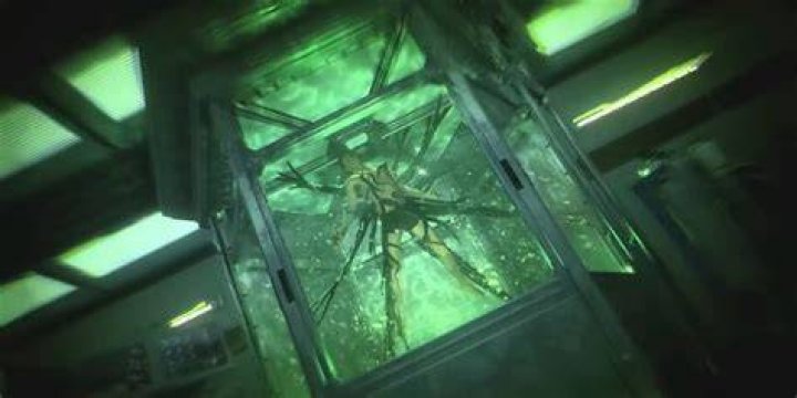 Harry, suspended in a tank with a green liquid, is overtaken by black, tree-like Symbiote limbs in a screenshot from Marvel's Spider-Man 2.