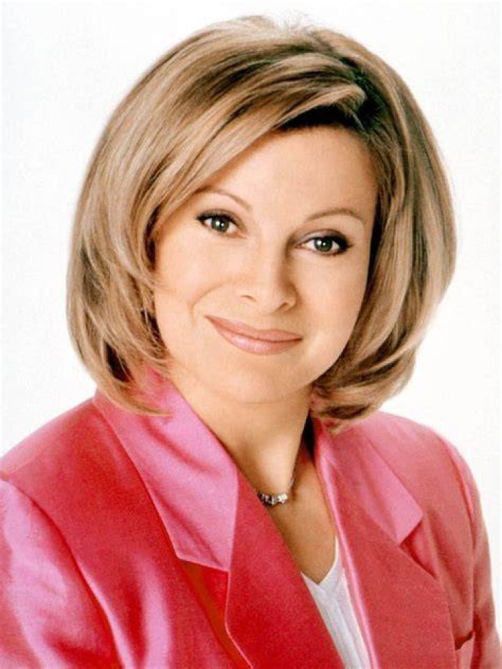 Jenny Jones in a red suit standing in front of her audience.