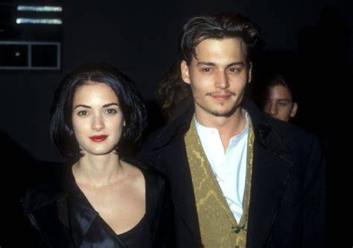 Johnny Depp and Winona Ryder stand looking out a window in Edward Scissorhands