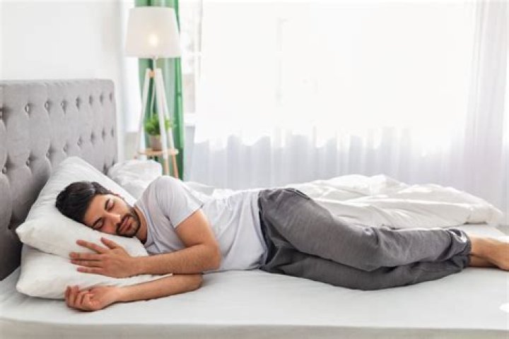 man is sleeping with a cat on a bed