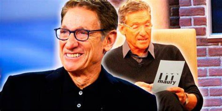 Maury Povich holding a piece of paper reading something with a guest sitting across from him on The Maury Povich Show.