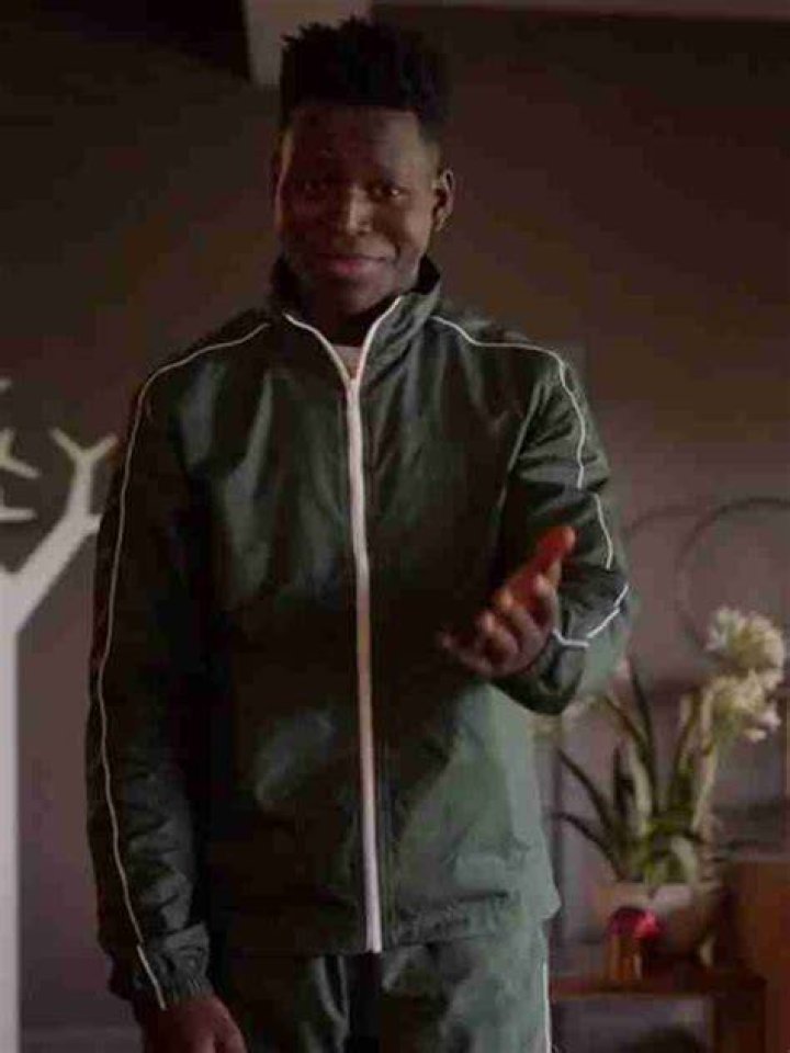 Sam wearing his green tracksuit in Rebecca's office