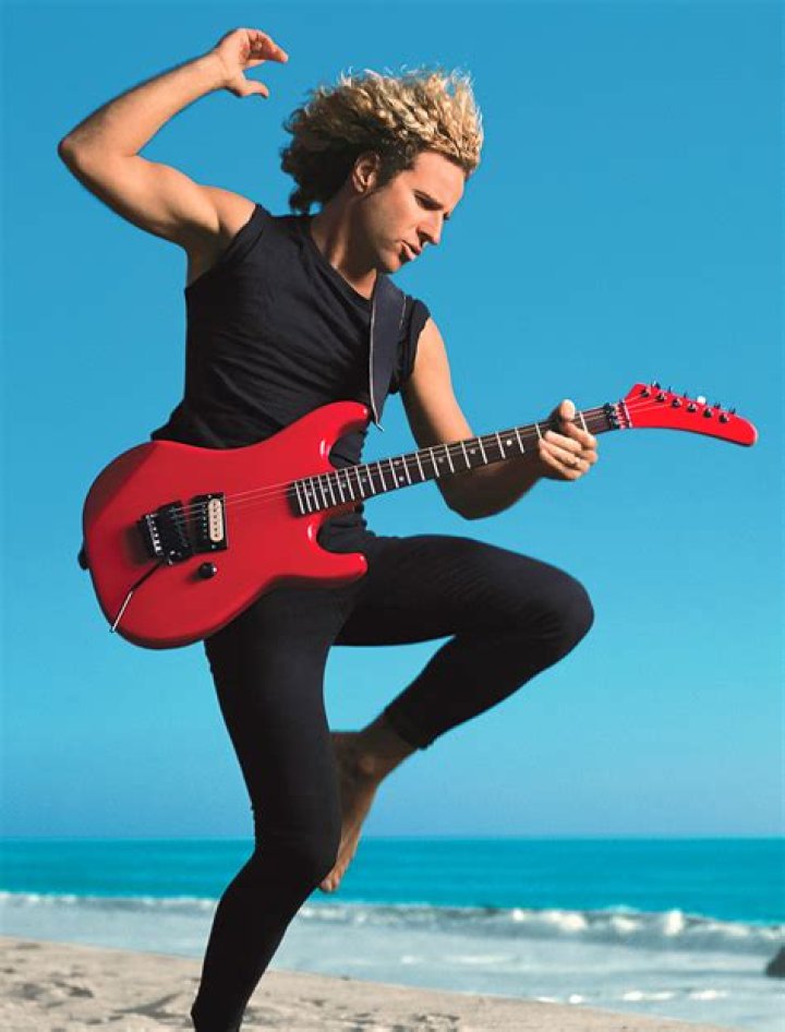 Sammy Hagar in a red tee playing guitar at a concert