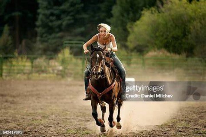 Woman riding horse in front of mountains in Estancia Nibepo Aike, El Calafate